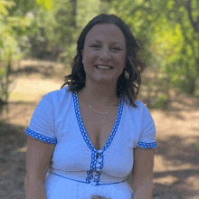 a woman in a white dress with blue trim is smiling