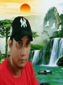 a man wearing a ny hat is standing in front of a waterfall .