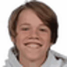 a young boy with brown hair is smiling and wearing a white sweater .