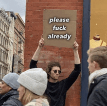 a man holds up a sign that says " please fuck already "