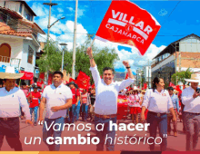 a man in a white shirt holds up a red flag that says villar cajamarca