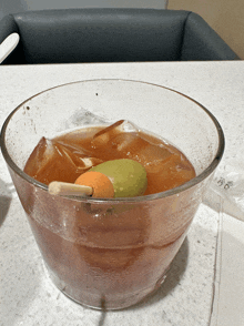 a bowl of iced tea with an orange and a green apple in it