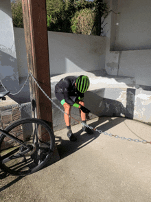 a person wearing a green helmet is chained to a post