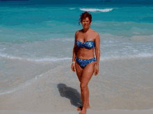 a woman in a bikini stands on a beach