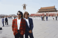 two men standing in front of a building with chinese writing