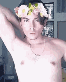 a shirtless man wears a flower crown on his head