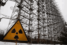 a yellow and black sign with a radioactive symbol on it is in front of a very tall building .