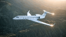 a small private jet is flying over a mountain range .