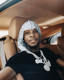 a man is sitting in the back seat of a car wearing a bandana .