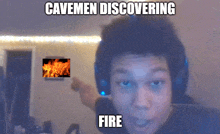 a man wearing headphones has a picture of a fire behind him and the caption cavemen discovering fire