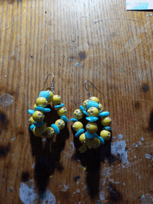 a pair of yellow and blue beaded earrings on a wooden surface