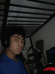 a boy wearing headphones looks at the camera in front of a laptop