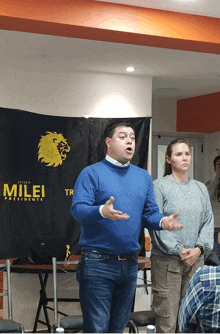 a man stands in front of a banner that says milei