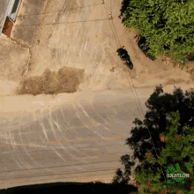 an aerial view of a person riding a motorcycle on a dirt road with an exatlon logo in the corner