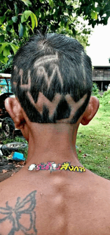 a man with a butterfly tattoo on his back has a crown cut into his hair