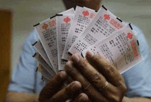 a man is holding a bunch of chinese lottery tickets in his hands .