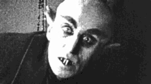 a black and white photo of a vampire with sharp teeth and horns .