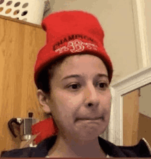 a woman wearing a red beanie is making a face .