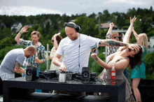 a group of people are dancing at a party with a dj playing music