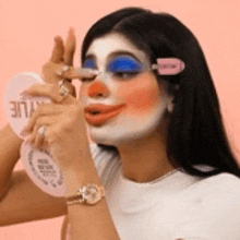 a woman with a clown face painted on her face is applying makeup .