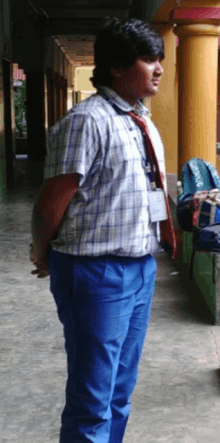 a man wearing a plaid shirt and blue pants is standing in a hallway