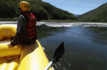 a man wearing a yellow helmet and a red vest that says ' chung ' on it sits on a raft