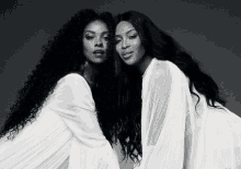 a black and white photo of two women with long hair standing next to each other