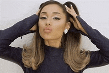 ariana grande is holding her hair in a ponytail and making a kissing face .