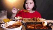 a woman in a red shirt is eating food from a bowl that says ' rice box ' on it