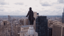 a statue of a man stands on top of a building in a city with a chase bank building in the background