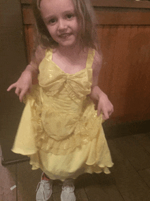 a little girl in a yellow dress and white shoes