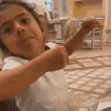 a young girl is sitting at a table with a glass of water and a fork in her hand .