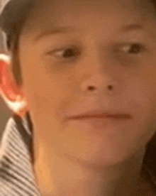 a close up of a young boy 's face wearing a baseball cap and a striped shirt .