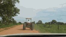 a man driving a tractor on a dirt road with a roof that says ' new holland ' on it