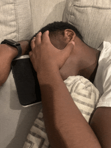 a man is laying on a couch with his hand on his head