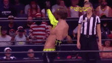 a referee in a striped shirt is standing next to a wrestler in a ring .