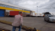 a man in a pink shirt is standing in front of a warehouse with a truck that says simply line on it