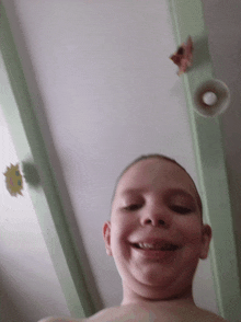 a young boy is smiling in front of a ceiling with a speaker on it