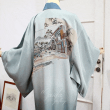 a light blue kimono with a painting of a village on the back