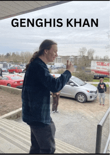 a man with long hair is standing in front of a parking lot with the name genghis khan on the bottom