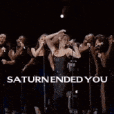 a group of people standing in front of a stage with saturn ended you written on it