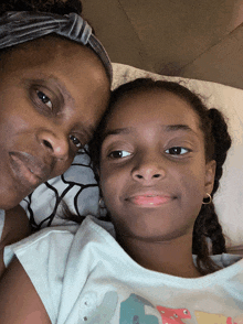 a woman and a little girl are laying next to each other on a bed