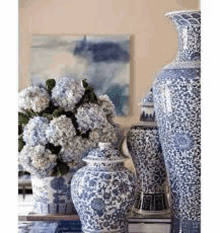 a group of blue and white vases sitting on top of a table with flowers in them .