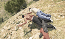 a man with a tattoo on his back is laying on the ground while another man holds a gun