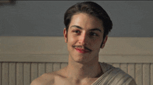 a shirtless young man with a mustache is smiling for the camera