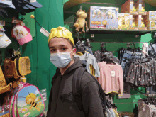 a boy wearing a mask stands in front of a shelf with maya toys