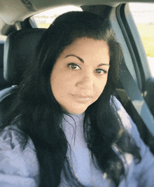 a woman in a purple sweater sits in the back seat of a car