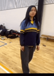 a woman in a blue and yellow striped shirt is standing on a wooden floor .