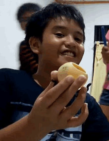 a young boy is holding a piece of fruit in his hand .