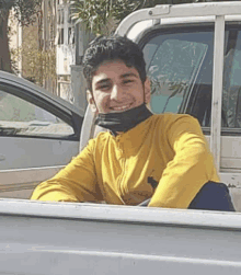 a young man is sitting in the back of a truck wearing a mask .